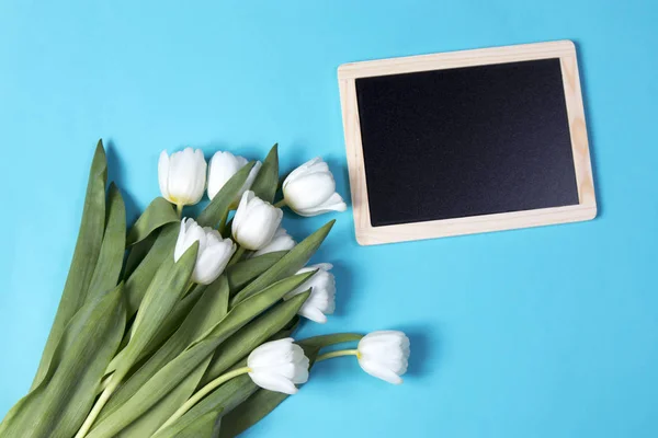 Ramo de tulipanes blancos con pizarra negra sobre fondo azul —  Fotos de Stock