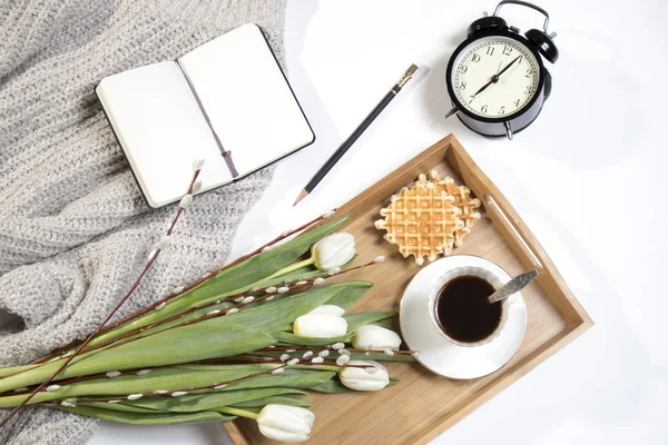 Bricka med kaffe, Vita tulpaner och vide står på sängen. Väckarklockan visar sju på morgonen. — Stockfoto