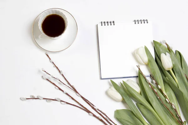 Den vita koppen kaffe på en vit anteckningsboken och en willow gren på ett vitt trä bord. — Stockfoto