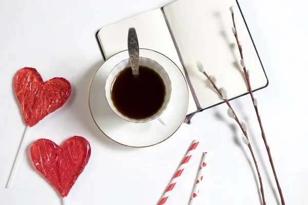 Uma xícara de café com um caderno e dois doces em forma de coração em uma mesa de madeira. Cartão para Dia dos Namorados, Dia das Mães — Fotografia de Stock