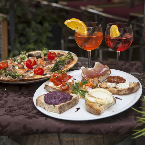 Wein in Gläsern, Teller mit Pizza und Sandwiches mit Marmelade und Käse auf dem Tisch am Eingang des Restaurants — Stockfoto