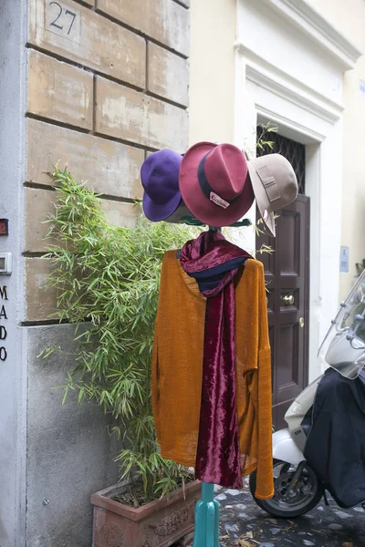 Brauner Umhang und farbige Hüte auf einem Kleiderbügel, der am Eingang des Ladens zum Verkauf steht — Stockfoto