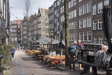 Kanal boyunca tipik eski Amsterdam binalar. Banklar insanlar. Lale Küvetler