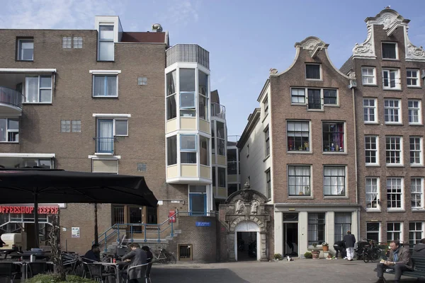 Typische oude Amsterdam gebouwen langs het kanaal. Mensen op de bankjes. Tulpen in kuipen — Stockfoto