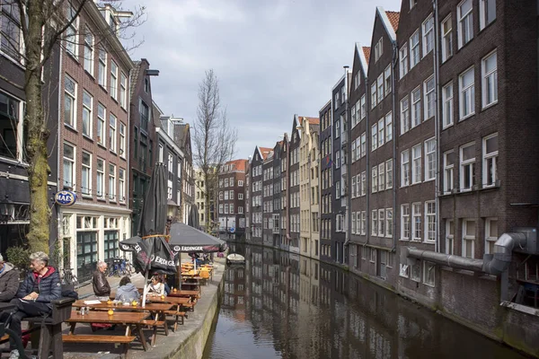 Typische oude Amsterdam gebouwen langs het kanaal. Mensen op de bankjes. Tulpen in kuipen — Stockfoto