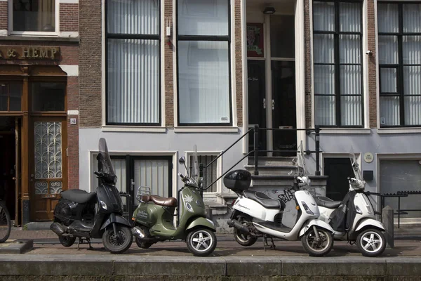 Motorfietsen en scooters geparkeerd in de buurt van het traditionele huis Amsterdam — Stockfoto
