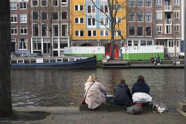 Drie vrienden zitten op het kanaal en chat in zonnige dag — Stockfoto