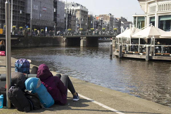 Туристы с рюкзаками сидят на берегу канала, отдыхают — стоковое фото