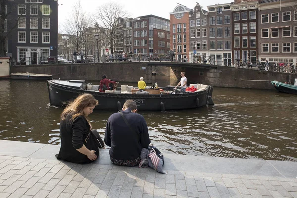 Toeristen zitten aan de oever van het kanaal, rust — Stockfoto