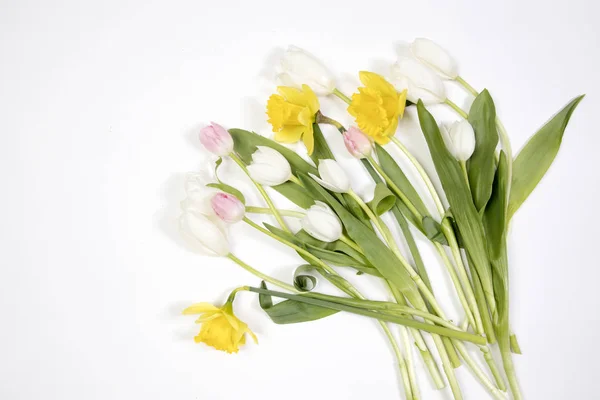 黄色のゴムブーツは、白とピンクのチューリップと黄色の水仙の花束。庭の付属品. — ストック写真