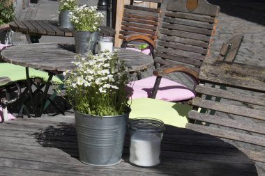 Bir sokak kafe tablolarda tencere lobularia ile süslenmiş. Sandalye sırtında beyaz battaniye