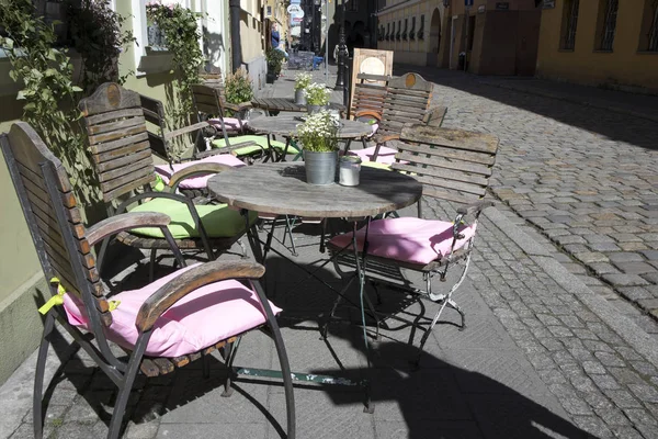 Mesas en un café de la calle decoradas con ollas con lobularia. Mantas blancas en el respaldo de las sillas — Foto de Stock