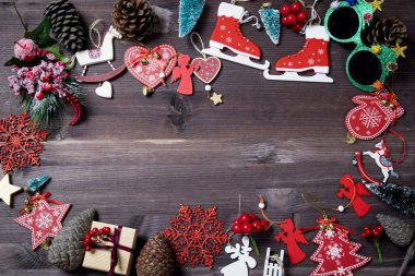 the Creative layout frame made of Christmas tree branches, paper card note, pine cones, gifts on brown wooden background. Xmas and New Year holiday. Flat lay, top view