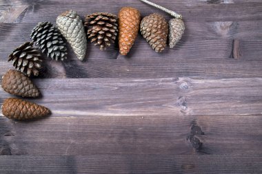 Kahverengi ahşap arka planda koniden yapılmış yaratıcı bir düzen. Xmas ve yeni yıl tatili. Düz yatış, üst görünüm