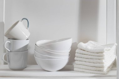 Mutfakta depolama sistemi var. Beyaz kupalar, kaseler ve havlularla raflarda.