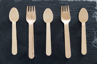 Kaşık ve siyah taş tahtadaki insanlar istediğiniz malzemelerle yemek ve tatmaya hazırlar..