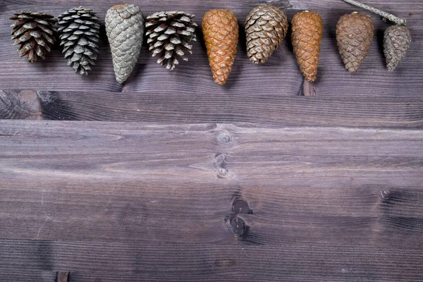 Creatieve lay-out frame gemaakt van kegel op bruine houten achtergrond. Kerstmis en nieuwjaarsvakantie. Vlakke lay, bovenaanzicht — Stockfoto