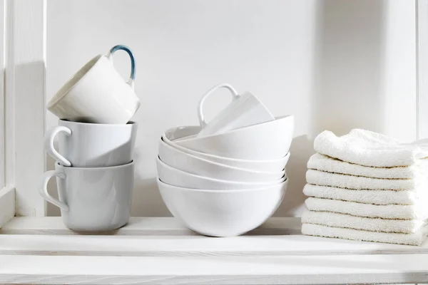 Storage system in kitchen. Shelving with white mugs, bowls and towels — Stock Photo, Image