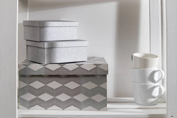 Storage system in the kitchen. Shelving with white mugs, and boxes