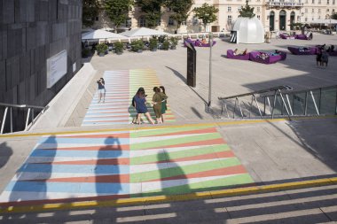 Viyana sanat pavyonu ve Mumok Müzesi. İnsanlar konserleri dinler, sandalyelerde oturur, mor banklarda uzanır..