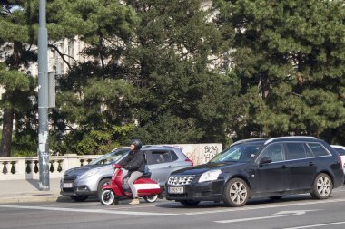 Trafik vardı, arabalar vardı ve kırmızı motorlu bir adam kask takıyordu trafik ışıklarında duruyordu.