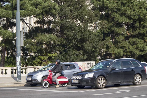 Verkeer op de weg, auto 's en een man op een rode motorola in een helm staan bij een stoplicht — Stockfoto