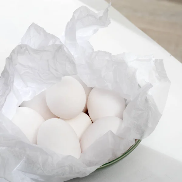 Kippeneieren verpakt in verfrommeld wit papier liggen op keukentafel. — Stockfoto