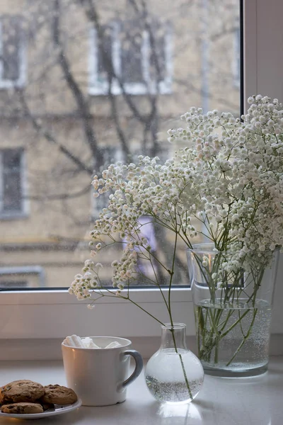 Buquê de Gypsophila na janela em um vaso de vidro ao entardecer . — Fotografia de Stock