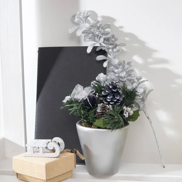 Christmas composition with fir branches in a gray pot, with notepad and a gift box with small sleds — Stock Photo, Image