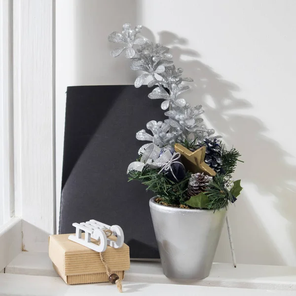 Vánoční skladba s jedlovými větvemi v šedém květináči, s poznámkovým blokem a dárkovou krabičkou s malými sáňkami — Stock fotografie