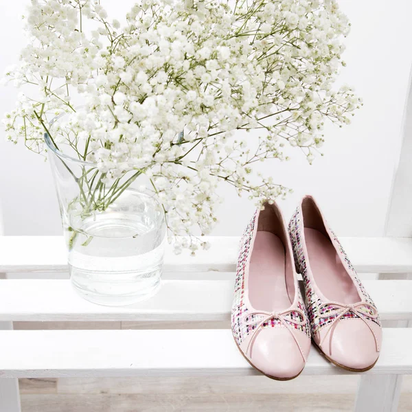 Bouquet of baby's breath in a transparent glass vase and pink shoes of the bride on a shelf — Stock Photo, Image