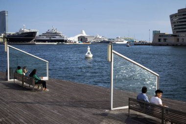 Turistler Barselona 'nın eski limanında martılarla çevrili olarak dinleniyorlar..