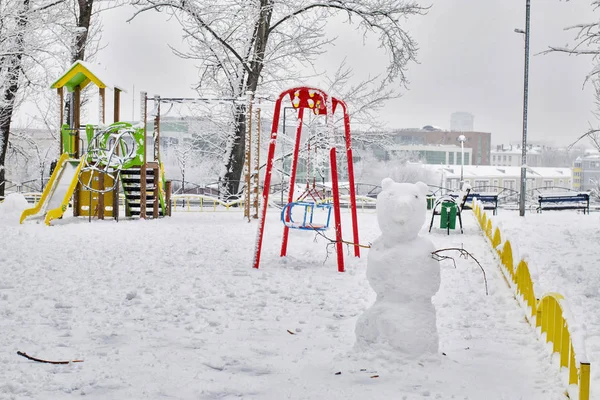 Salıncaklı oyun alanı ve banklarda kardan adamlar. — Stok fotoğraf