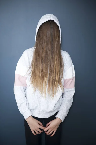 Joven en una sudadera con capucha, pelo bloqueando su cara, su cara no es — Foto de Stock