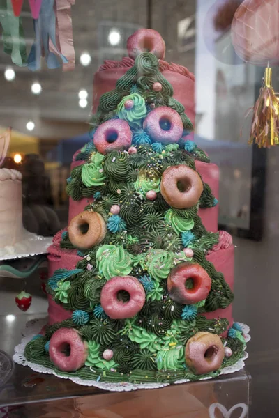 Bolo colorido em forma de árvore de Natal é exibido em uma janela da loja . — Fotografia de Stock
