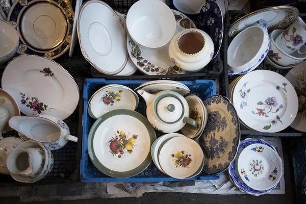 Il tè multicolore e i set da pranzo in un mercato delle pulci in vendita — Foto Stock
