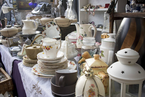 На блошином рынке продаются разнообразные блюда, старые телефоны, вазы, кувшины, лампы
