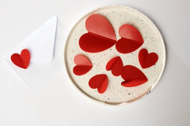 Beyaz seramik tabakta kırmızı plastik kalpler. Sevgililer günü kartı.
