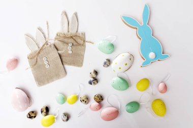 Beyaz tepside bıldırcın yumurtası. Dekorasyon. Beyaz arka planda tavşan şeklinde düğmeleri olan tuval hediye paketleri. Paskalya kartı. Boşluğu kopyala