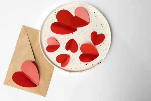 白いセラミック皿の中の赤いプラスチック製の心。バレンタインカード — ストック写真