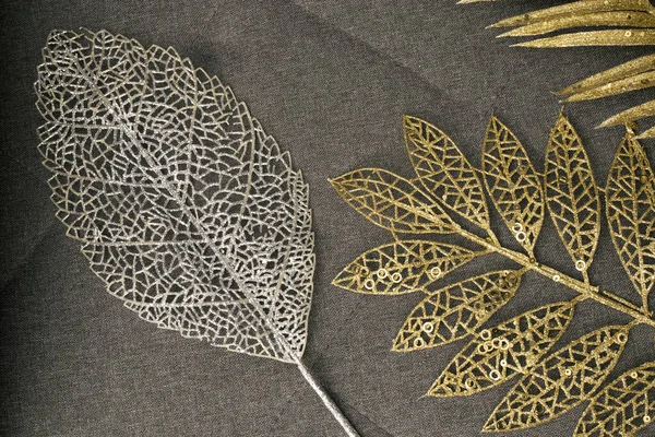 Plastic gold and silver branches of exotic plants on gray fabric sofa — Stockfoto