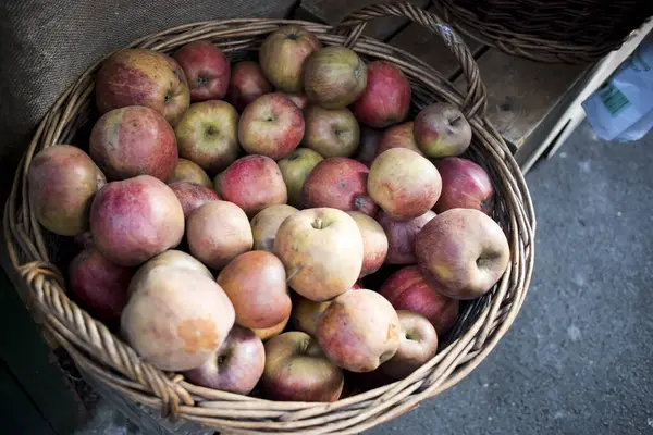 Panier en osier plein de pommes rouges et jaunes à vendre sur le marché . — Photo