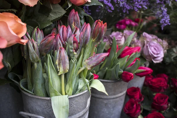 Sträuße von rosa Rosen und roten Tulpen in großen Zinkeimern zum Verkauf im Geschäft. — Stockfoto