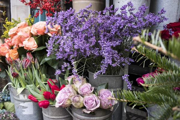 Kytice z růžových růží a červených tulipánů, zelené hortenzie v pastelových barvách ve velkých zinkových kbelících na prodej v prodejně. — Stock fotografie