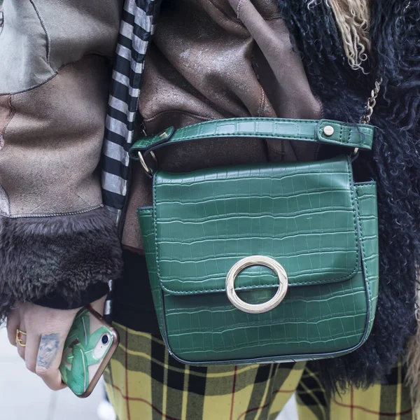 stylish woman of fashionable woman has a small quilted green leather bag in her hands. Hit of the season, super cool thing for summer