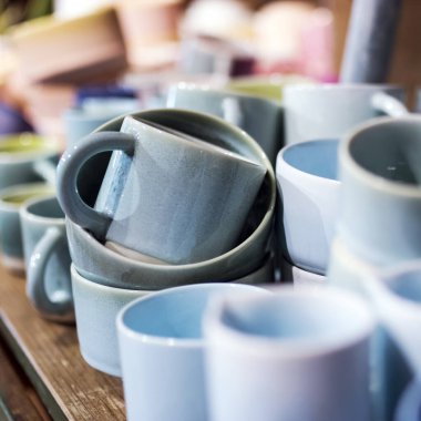 Mağazadaki bir rafta mavi bardaklar. Desenci seramik plakalar. Masa düzenleme, sofra takımı ve yeme konsepti. Süpermarketin raflarında çeşitli şık yemek çeşitleri.