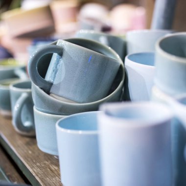 Mağazadaki bir rafta mavi bardaklar. Desenci seramik plakalar. Masa düzenleme, sofra takımı ve yeme konsepti. Süpermarketin raflarında çeşitli şık yemek çeşitleri.