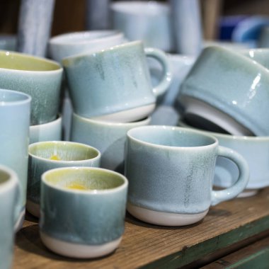 Mağazadaki bir rafta mavi bardaklar. Desenci seramik plakalar. Masa düzenleme, sofra takımı ve yeme konsepti. Süpermarketin raflarında çeşitli şık yemek çeşitleri.