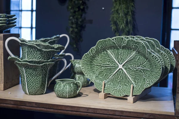 Green ceramic plates on a shelf in a store. Designer ceramic plates with a pattern. Table setting, tableware and eating concept. Various Types Of fashionable set of dishes on supermarket shelves