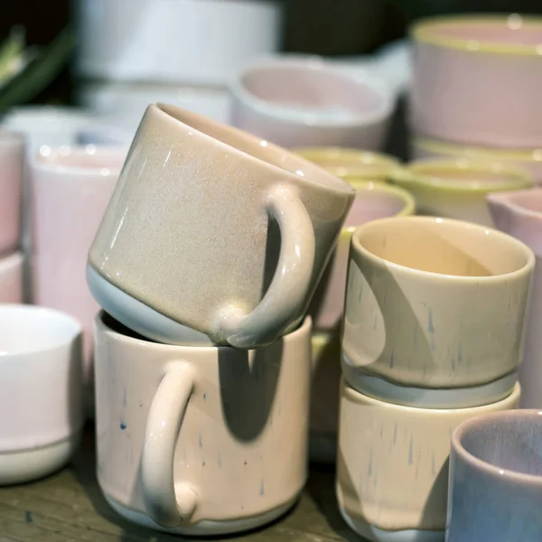 beige ceramic cup on a shelf in a store. Designer ceramic plates with a pattern. Table setting, tableware and eating concept. Various Types Of fashionable set of dishes on supermarket shelves